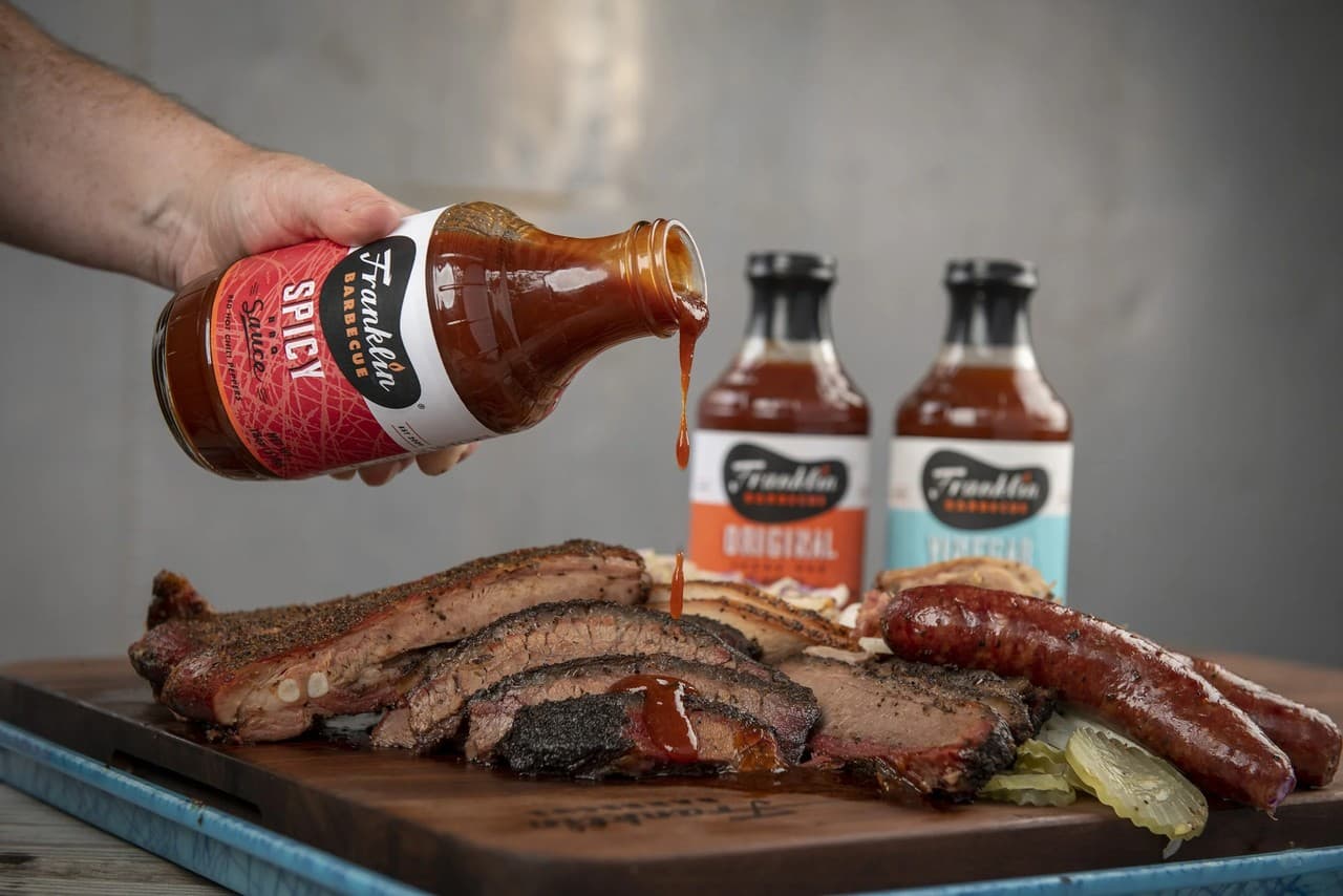 Barbecue sauce poured over freshly smoked meats on a cutting board at Franklin Barbecue